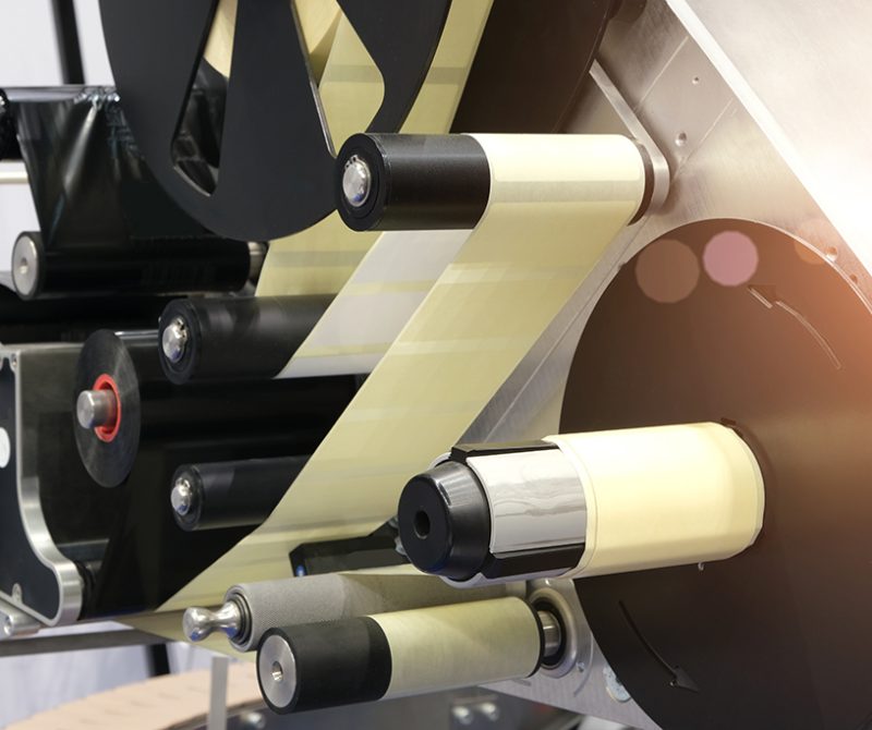 Fragment of the conveyor of sticking labeling machine. Abstract industrial background.